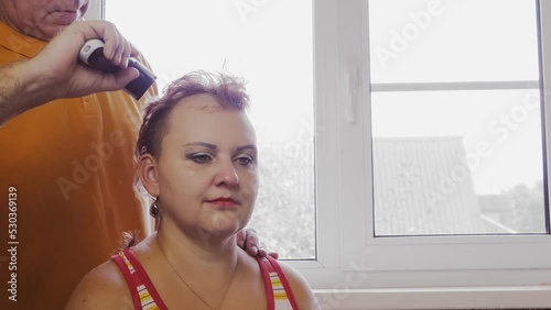 A husband shaves his Jewish wife baldly with a clipper Orthodox community. Medium plan photo