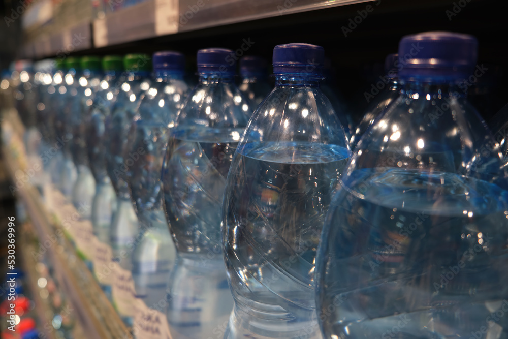 Spring water on a supermarket shelf in plastic bottles. Closeup selective focus. Spring water on a supermarket shelf in plastic bottles. Closeup selective focus.