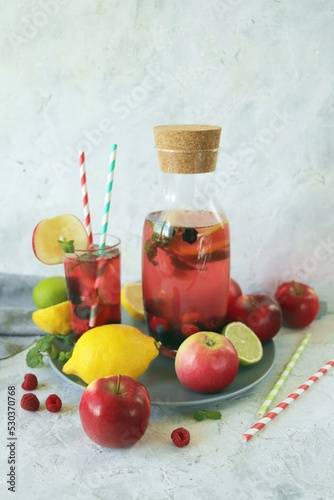Detox drink from apples  berries  mint and citrus in glasses and in a decanter  on the table  seasonal drinks from organic natural ingredients
