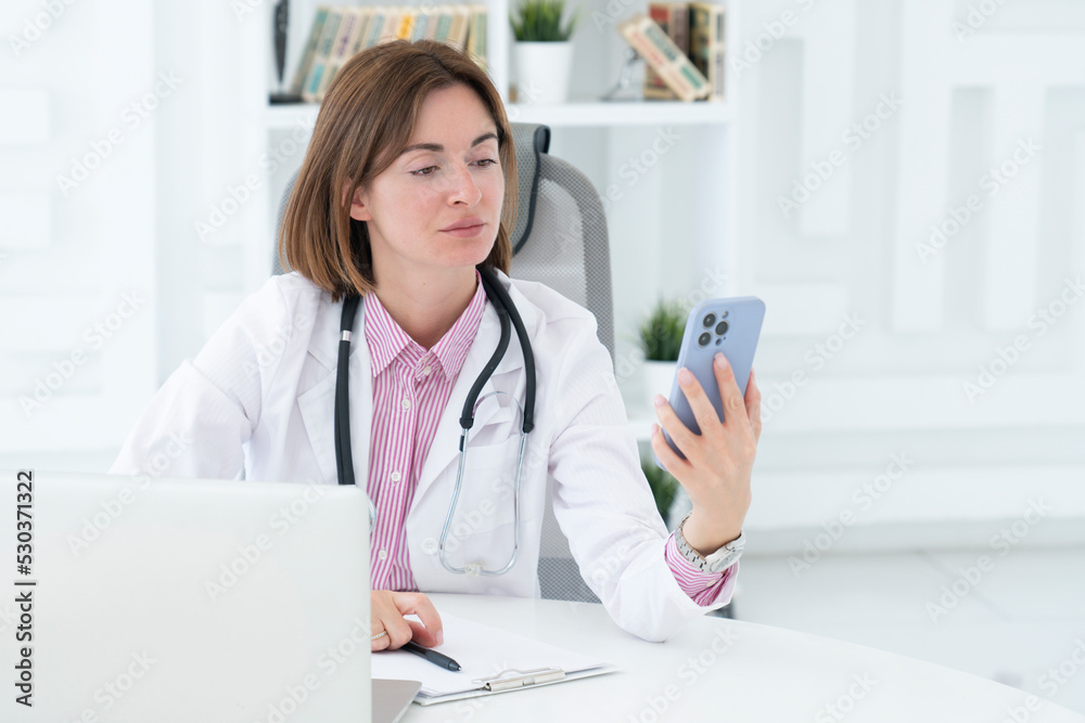 Portrait of attractive female doctor looking at phone and working in her modern office Portrait of attractive female doctor looking at phone and working in her modern office