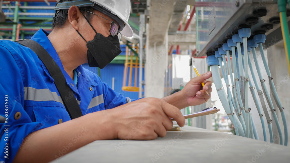 Industrial electrician wearing safety helmet Visual check electrical