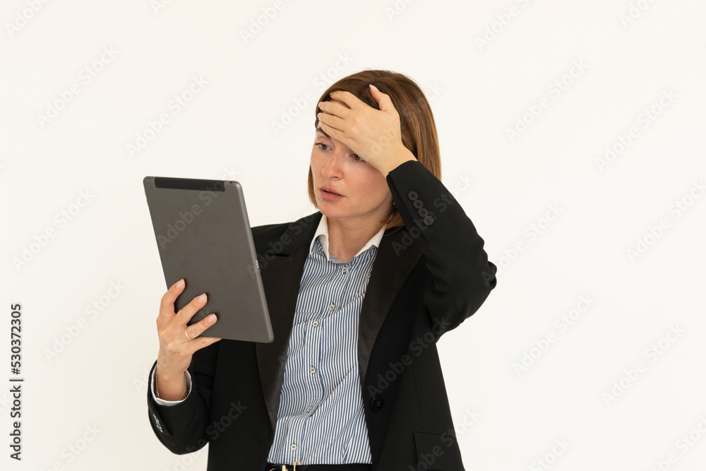 Young attractive business woman in black suit holding gadget and putting hand on her head isolated on white. Copy space and place for text concept Young attractive business woman in black suit holding gadget and putting hand on her head isolated on white. Copy space and place for text concept