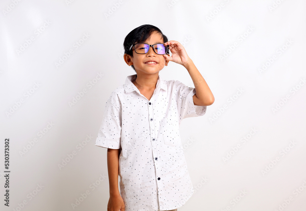 Happy asian schoolboy standing while holding eyeglasses. Isolated on white background Happy asian schoolboy standing while holding eyeglasses. Isolated on white background