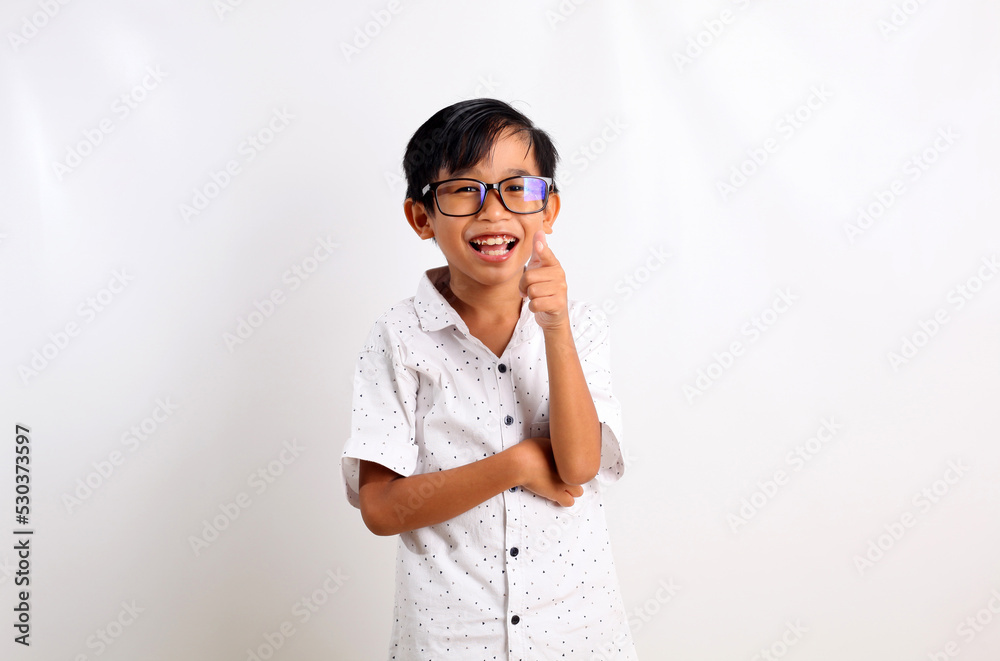 Happy asian boy standing while pointing and looking at the camera. Isolated on white background Happy asian boy standing while pointing and looking at the camera. Isolated on white background