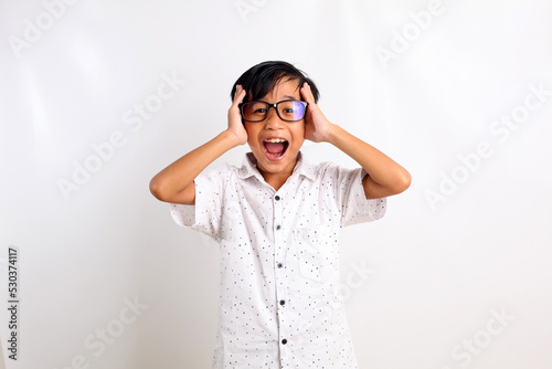 Happy surprised asian boy standing while screaming with unbelievable expression. Isolated on white