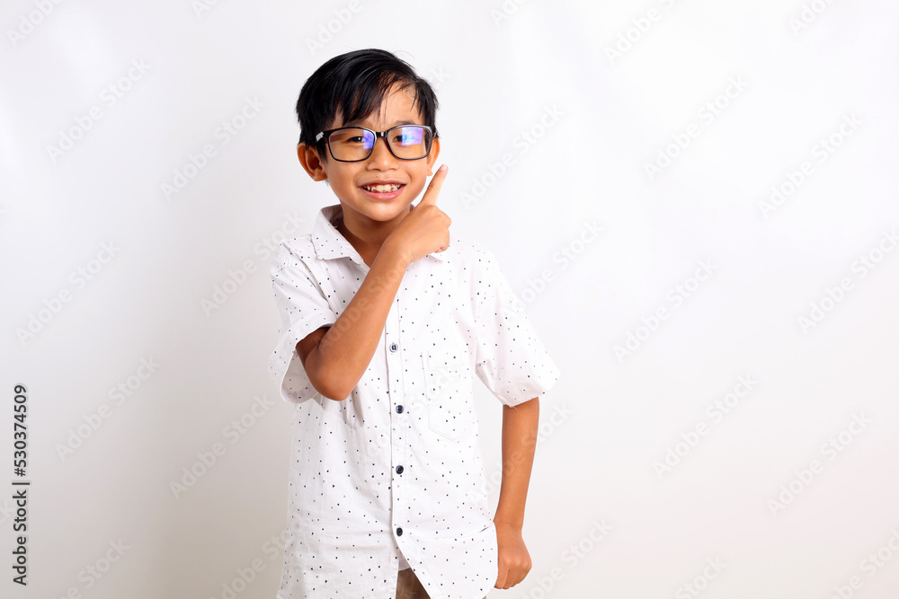 Adorable asian boy standing while pointing up with his finger. Isolated on white background Adorable asian boy standing while pointing up with his finger. Isolated on white background