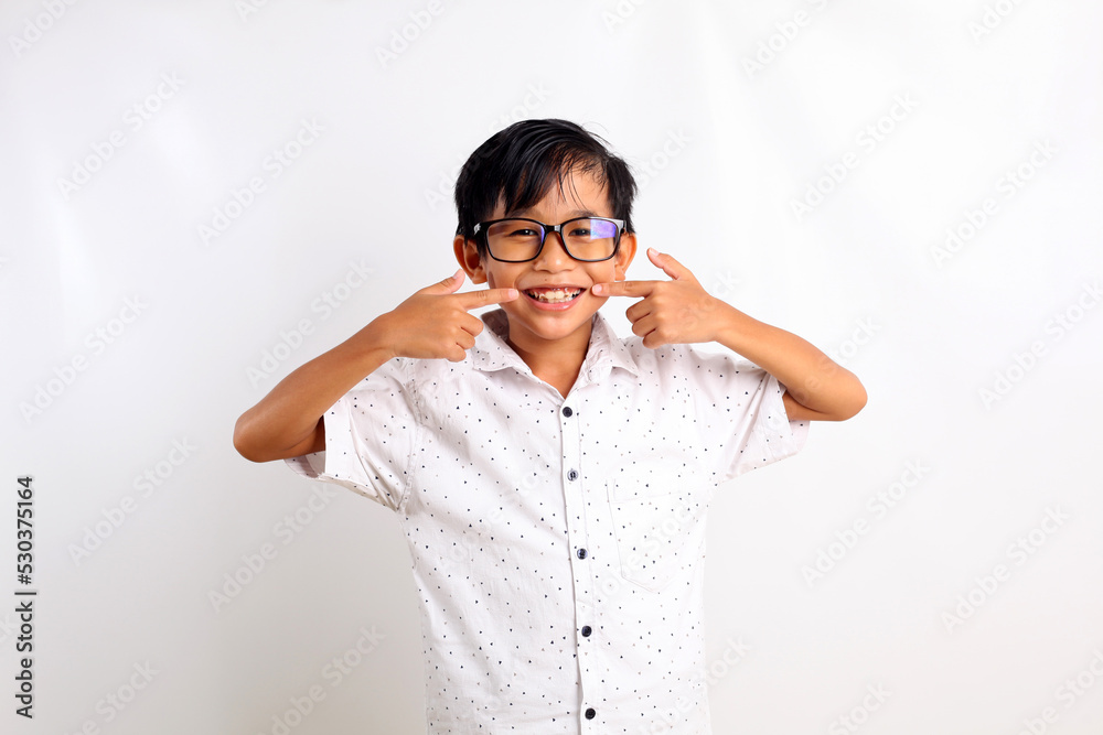 Cheerful asian boy standing while smiling and pointing his mouth. Isolated on white background Cheerful asian boy standing while smiling and pointing his mouth. Isolated on white background