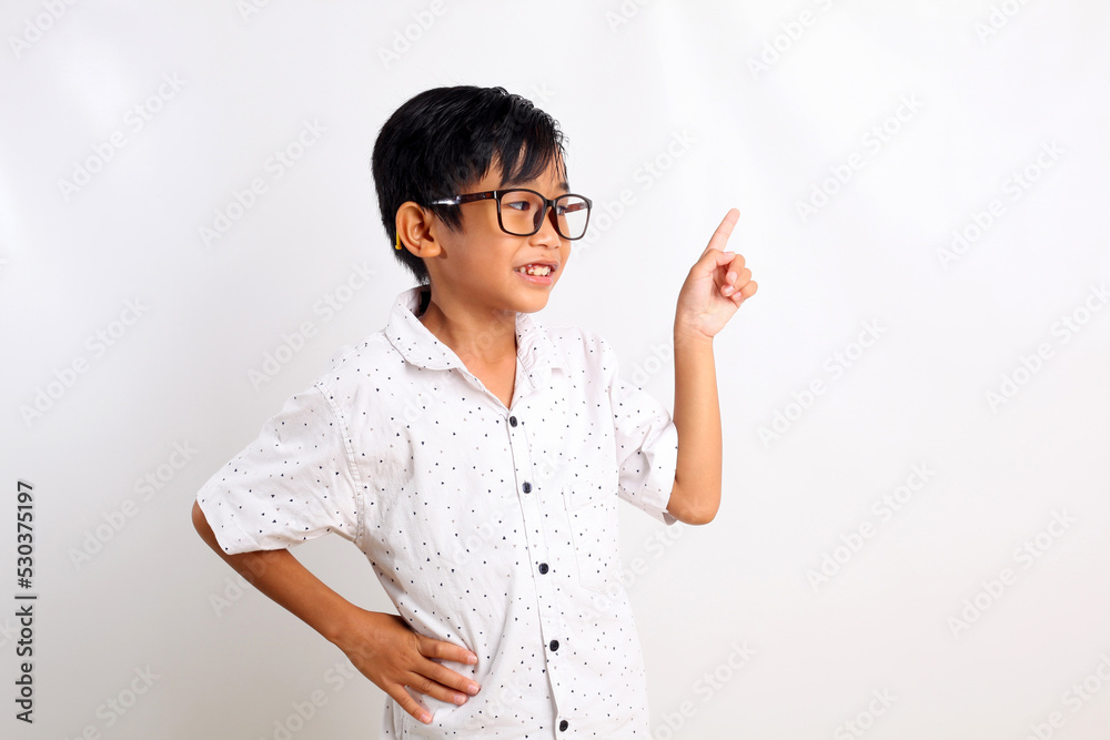 Happy asian boy standing while looking sideways and pointing something. Isolated on white background Happy asian boy standing while looking sideways and pointing something. Isolated on white background