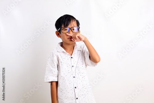 Asian little boy standing while showing bad smell expression gesture. Isolated on white background