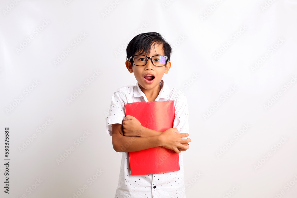 Surprised asian schoolboy standing while carrying a book. Isolated on white background Surprised asian schoolboy standing while carrying a book. Isolated on white background