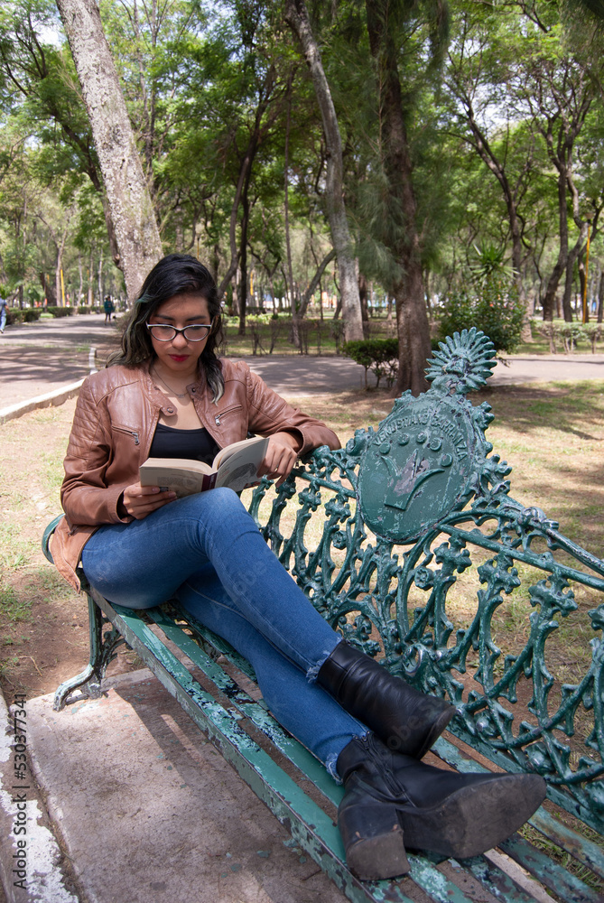 portrait of a beautiful latina woman sitting on a bench in the park reading a book portrait of a beautiful latina woman sitting on a bench in the park reading a book