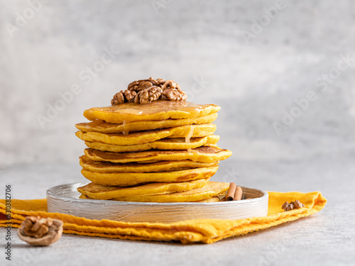 Pumpkin (squash) pancakes stack. Autumn breakfast, seasonal baing. Close up view. Orange crepes with honey and walnuts. photo