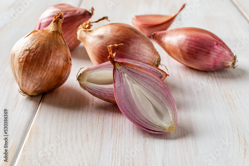 Canvastavla Halved red eschalot and whole bulbs on a white wooden table