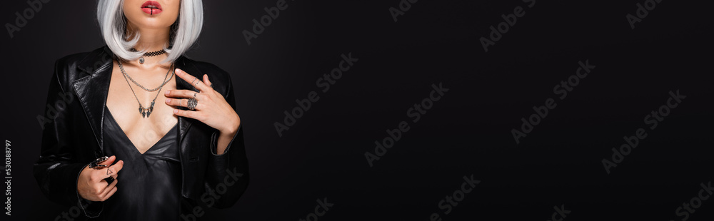 partial view of sexy witch style woman in leather jacket with decollete isolated on black, banner.