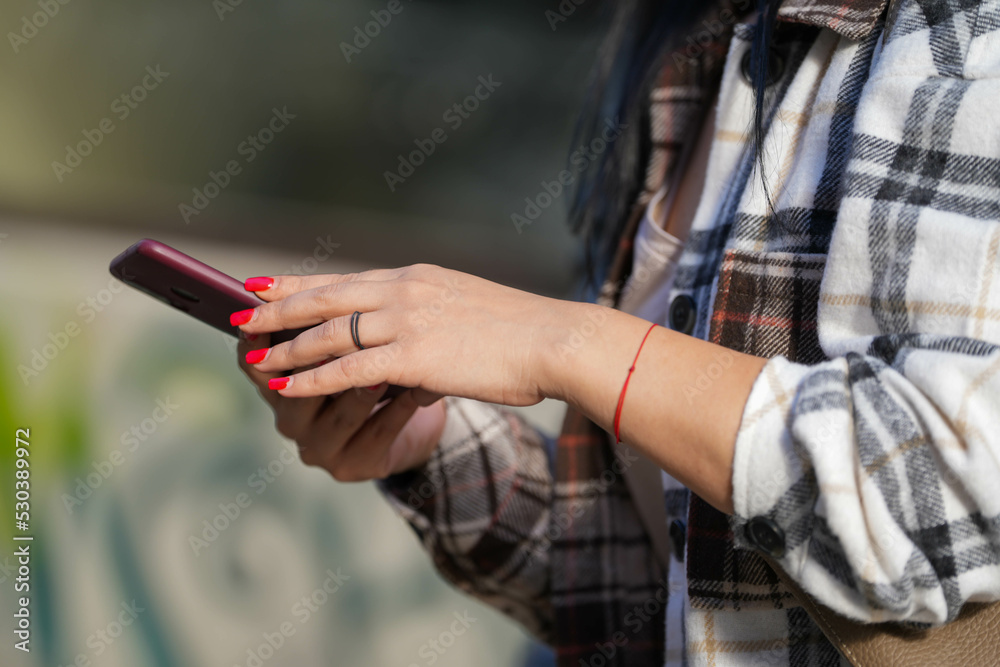 woman's hands holding a smartphone. woman with red nails. detail.