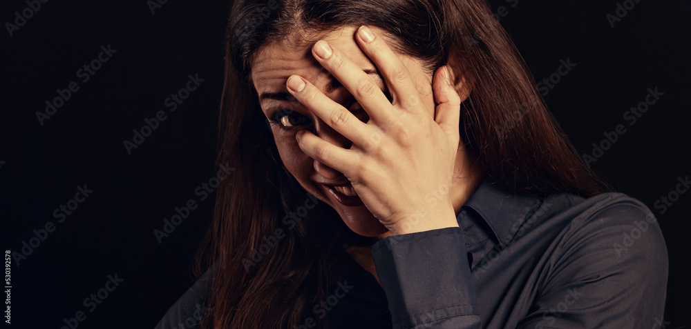 Happy chuckling fun business beautiful woman covering and hiding the face the hand on blue shirt on black background with empty copy space. Closeup Happy chuckling fun business beautiful woman covering and hiding the face the hand on blue shirt on black background with empty copy space. Closeup