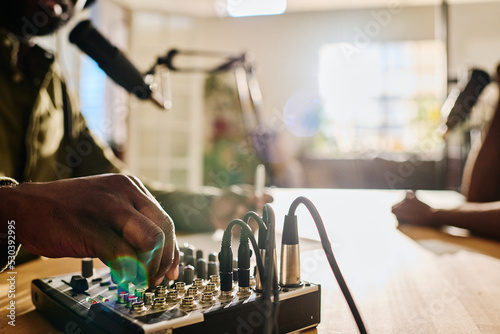 Quadro em tela Hand of young African American man rotating consoles on soundboard while regulat