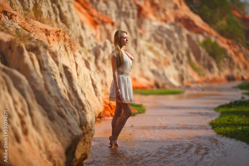 A beautiful young woman walks along a stream in the tropics. Vietnam Mui Ne. Blonde in the tropics