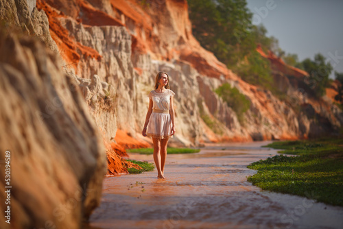 A beautiful young woman walks along a stream in the tropics. Vietnam Mui Ne. Blonde in the tropics
