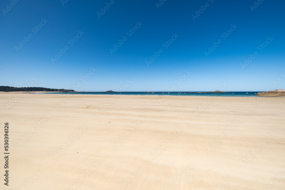 Large sandy beach in the town of "Sables d'or les pins" in Brittany at low tide in summer - obrazy, fototapety, plakaty 