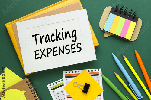 Track Expenses - white paper with text on green background