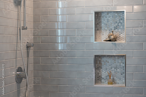 Modern bathroom details of gray tile shower with decorative insets and chrome finishes. photo