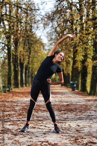 Fototapeta Naklejka Na Ścianę i Meble -  positive middle age woman stretching outdoors preparing for exercise in sportswear