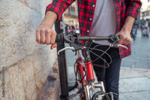 Man in plaid shirt with a bike in the street