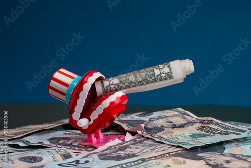Concept of wild capitalism, representation of the voracity of capitalism through a mouth with legs and a USA hat smoking a hundred dollar bill, while trampling on a pile of dollars. photo