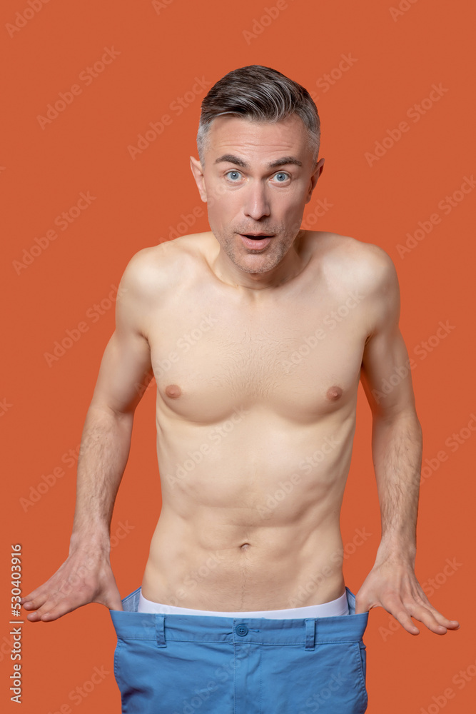 A man in shorts with flat belly looking emotional and surprised