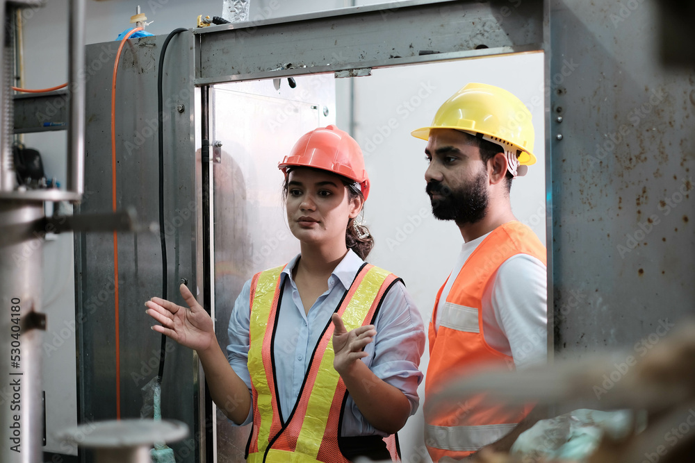 engineer worker working together with safety uniform and white helmet to work in industry factory handle tablet. Factory worker inspecting production line of drink production in factory. indian men