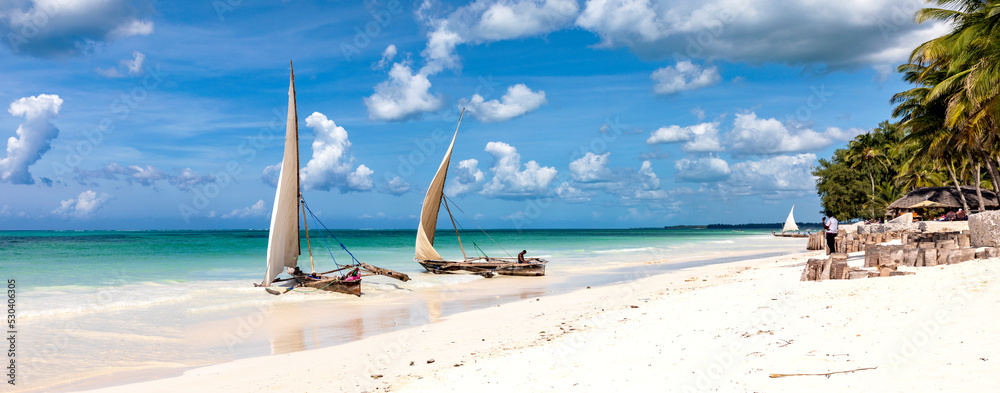 Traditionelle Dhows an einem Strand auf Sansibar. Boote im türkisfarbenes Ozean und blauer Himmel in Tansania, Panorama. - obrazy, fototapety, plakaty 