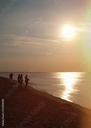 Sunset over the Baltic Sea. The Curonian Spit near Kaliningrad. People walk along the beach and admire the views