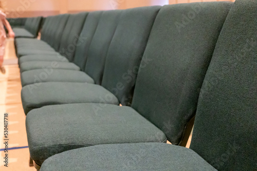 selective focus on a padded seat cushion of a row of chairs in a auditorium. 