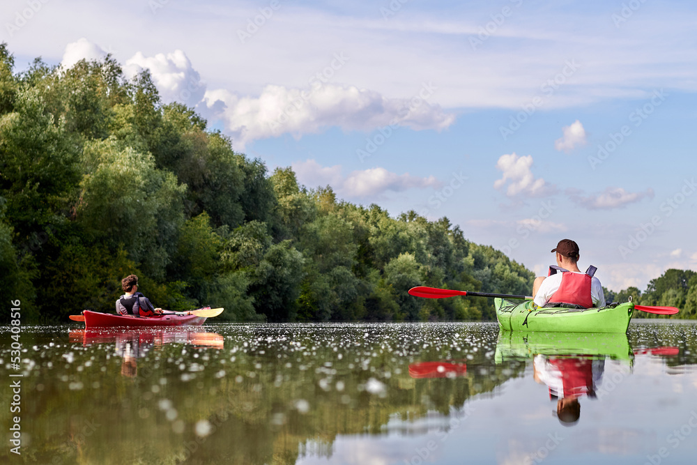 Kayaking on the river. Back view of two young men are sitting in kayaks ...