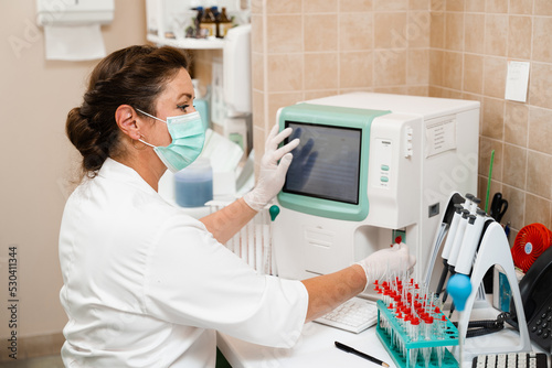 Laboratory assistant works on blood analyzer and makes hematological analysis in the laboratory. Medical equipment in the lab. Biochemical and hematological analysis of blood. photo