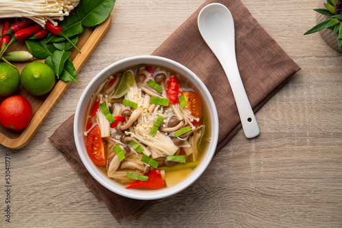 Thai vegan food ,Mushroom Tom Yum ,Spicy clear soup with enoki mushroom and brown shimeji mushroom in white bowl.Top view
