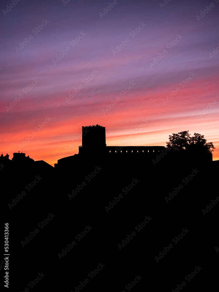 silhouette  profile of medieval castle  on top of hill at sunset