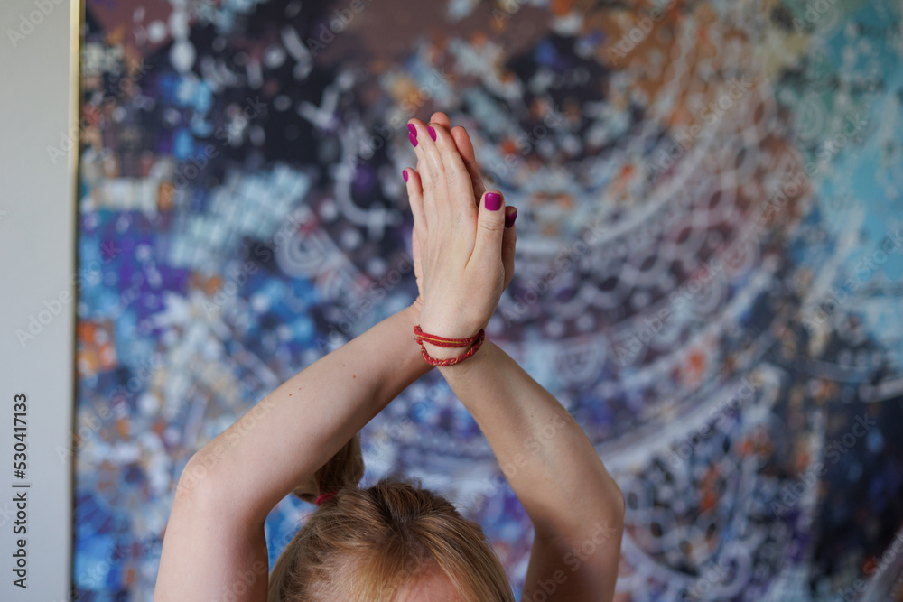 Fototapeta premium Closeup of woman hands in yoga pose. Woman hands doing pilates exercises. Beautiful palm with pink manicure. Flexible blond girl doing yoga poses indoors 