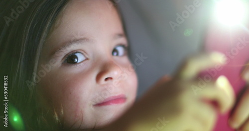 Child girl turning cellphone flashlight ON