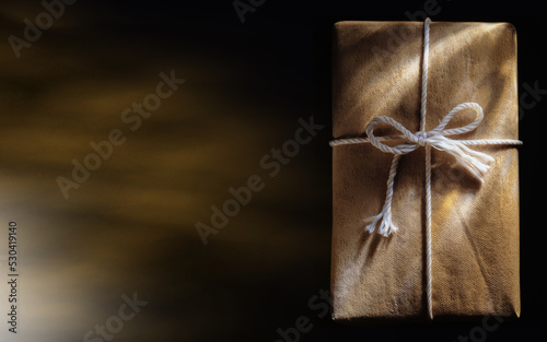 Handmade gift box with white tie, isolated on black. Horizontal photo