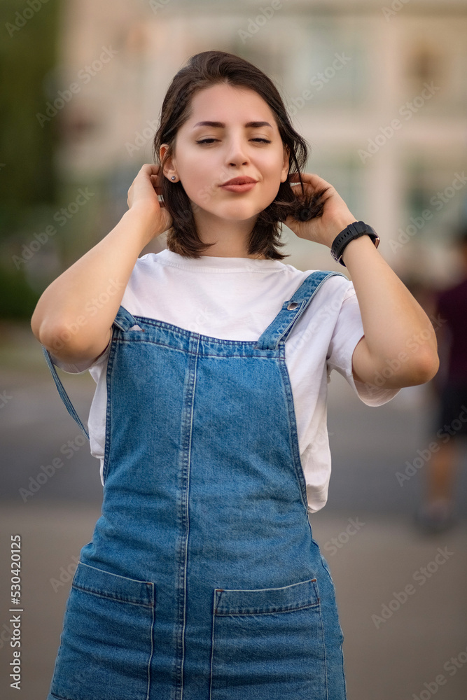 Portrait of a young beautiful dark-haired girl in a denim dress.
