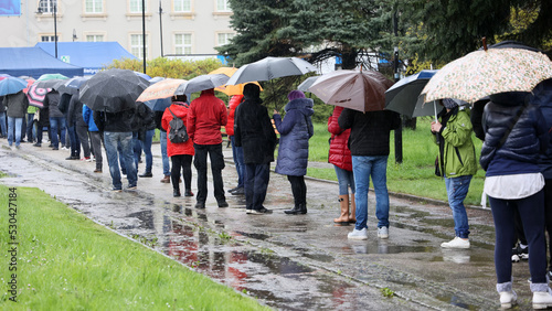  Ludzie pod parasolami czekają w kolejce do mobilnego punktu szczepień we Wrocławiu