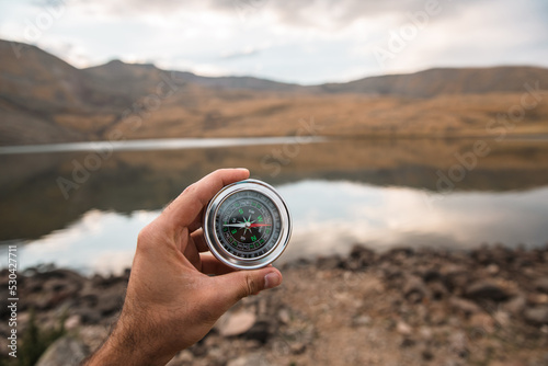 man holding compass on lake background