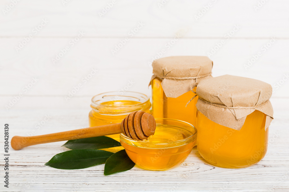 Honey in jar with leaves and honey dipper on colored background top view with copy text Honey in jar with leaves and honey dipper on colored background top view with copy text