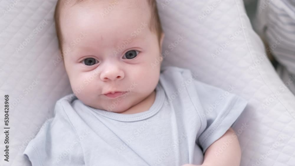 Portrait newborn baby boy lying in nursery cocoon with blue clothes on bed in bedroom at home, happy baby morning Portrait newborn baby boy lying in nursery cocoon with blue clothes on bed in bedroom at home, happy baby morning