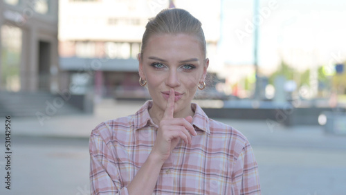 Outdoor Young Woman with Finger on Lips, Please be Quiet © stockbakers