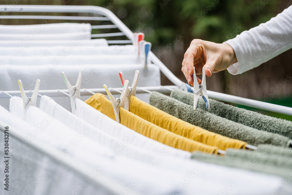 woman hand hanging clean wet clothes on drying rack outdoors, obrazy