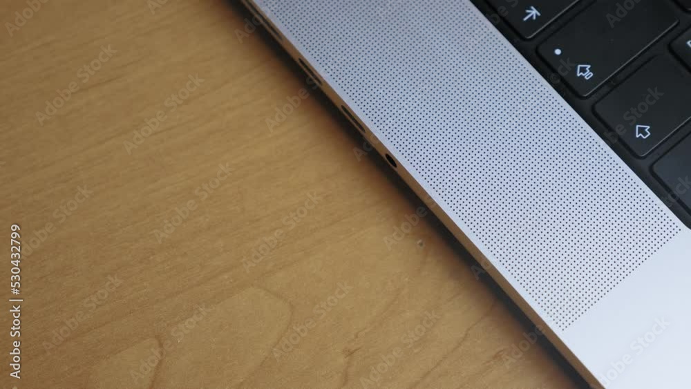 A person pulls out headphones into the headphone jack of a laptop