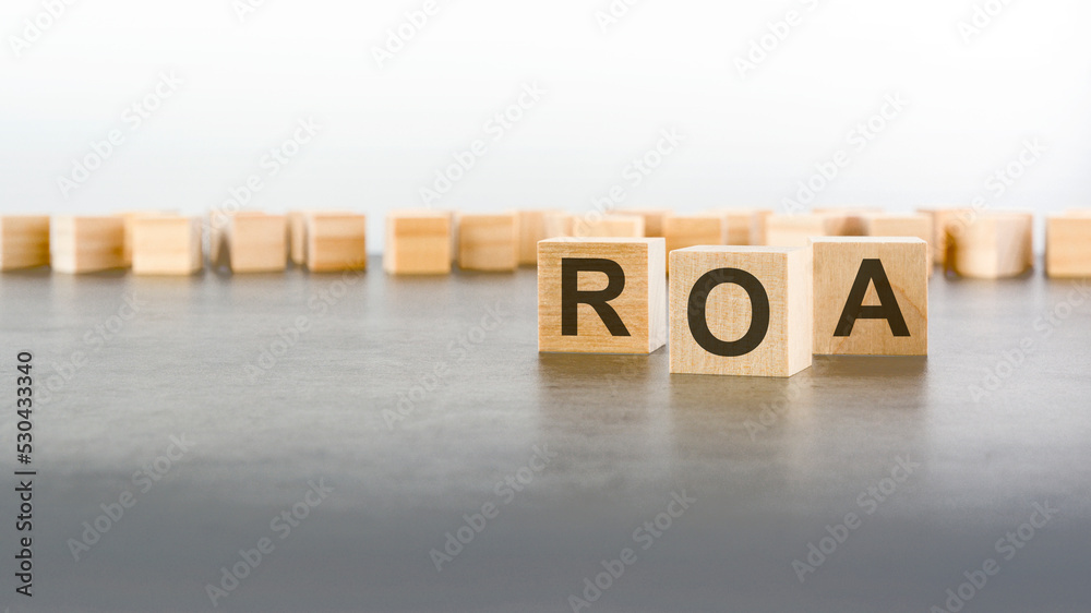 Obraz premium text ROA on wooden cubes on gray background. abbreviation of 'Return on Assets'. square wood blocks. top view, flat lay.